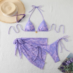 Three-piece purple floral bikini set featuring a wrap skirt and golden flower metal detail