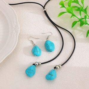 Close-up of vintage turquoise heart pendant necklace and matching drop earrings on white cloth