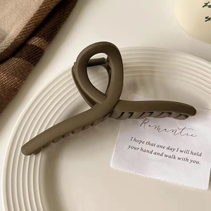 Gros plan d'une pince à cheveux croisée marron mat sur une assiette décorative