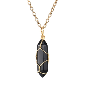 Detailed macro view of handmade wire-wrapped black hexagonal stone pendant on gold chain