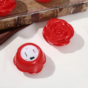 Luminous red rose LED night light with white battery base on a vintage book