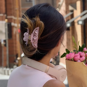 Gros plan d'une pince à cheveux papillon en acétate rose marbré avec détails ajourés