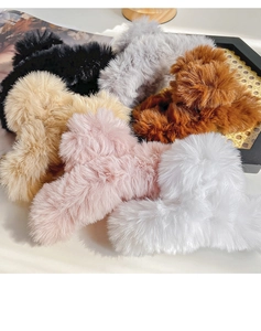 Detailed view of large plush hair claws in six colors displayed on a woven tray