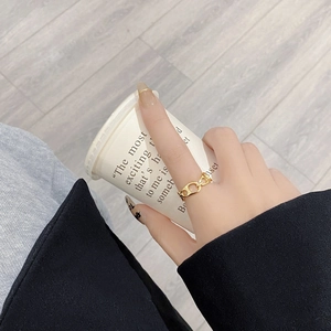 Close-up of golden interlocking chain ring worn on finger with minimalist design