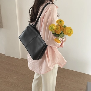Minimalist black leather tote bag for women shown on a model during daily commute