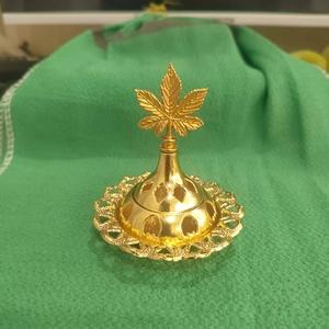 Detail of golden metal incense burner with hollow pattern and leaf-shaped top ornament