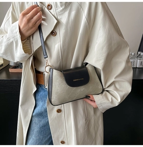 Detail of minimalist beige fabric shoulder bag with black leather flap and gold hardware