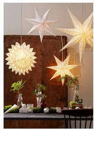 Close-up of hanging paper star lanterns with intricate cutouts and warm white glow