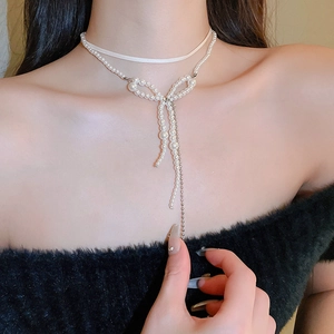 Elegant double-layered necklace featuring silk choker and pearl bow pendant with long tassel