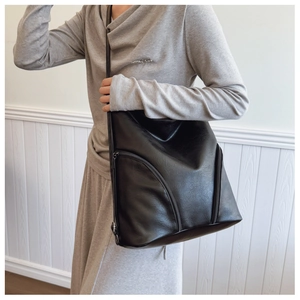 Detail of soft black PU leather texture and zipper on a large capacity shoulder bag