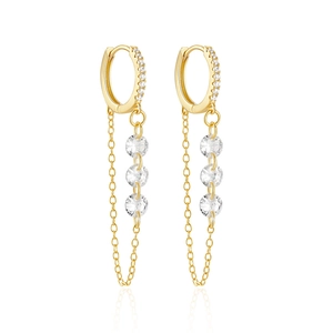 Macro detail of gold tassel earrings with zircon stones and fine metal chains