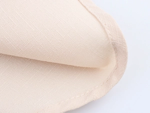 Dettaglio dell'abito beige con scollo all'americana che mostra la trama del tessuto e cuciture