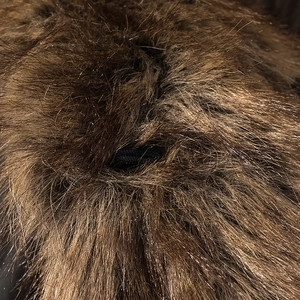 Close-up of brown faux fur texture featuring a black elastic loop detail on the jacket