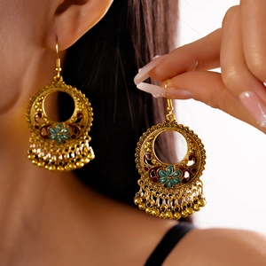 Detail of bohemian gold hoop earrings with blue floral enamel and metal bead tassels