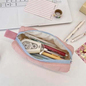 Pink quilted pencil case with blue zipper showing internal storage space for stationery