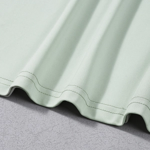 Dettaglio dell'orlo con doppia cucitura rinforzata su tessuto a maglia verde