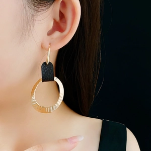 Macro shot of gold textured hoop earrings with black snakeskin leather detail
