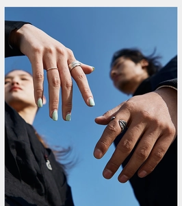 Outdoor shot of silver feather rings for couples set against a clear blue sky background
