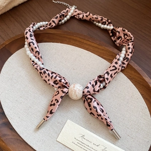 Détail du collier en tissu imprimé léopard avec perles nacrées et perle à motif marbre