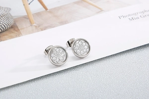 Close-up of silver hollowed-out round earrings with inlaid imitation diamonds for women