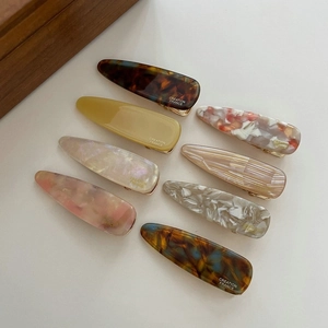 Detail view of eight colorful resin hair clips with elegant ink-smudge texture