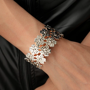 Macro shot of silver metallic flower cuff bracelet with layered daisy pattern detail
