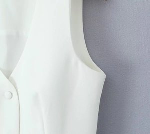 Detail view of white vest featuring professional tailoring and fabric-covered button