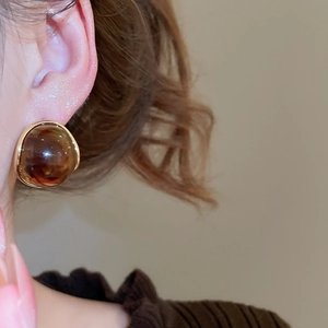 Close-up of vintage amber resin round stud earrings with golden textured metal trim