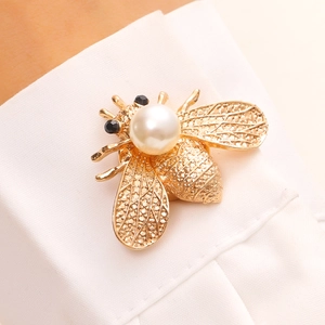 Gros plan d'une broche abeille dorée avec perle et cristaux sur un col de chemise
