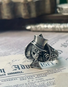 Gros plan de la bague punk crâne en argent avec design pique sur fond vintage