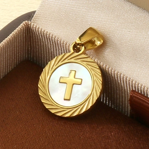 Détail d'un pendentif rond en acier doré avec croix sur nacre dans son écrin à bijoux