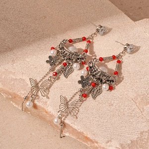 Detail view of vintage butterfly earrings with red beads and long pearl tassels