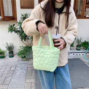 Detailed close-up of mint green quilted bag with floral patterns and soft padded texture
