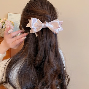 Detailed view of a pink satin polka dot bow hair clip for elegant women styling