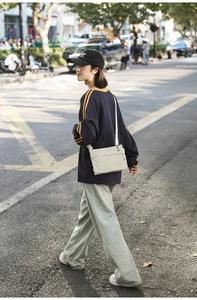 Close-up of lightweight nylon crossbody bag in beige featuring multiple zipper pockets