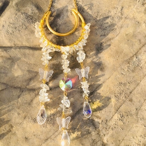 Detailed view of crystal suncatcher with golden ring and butterfly charms on concrete