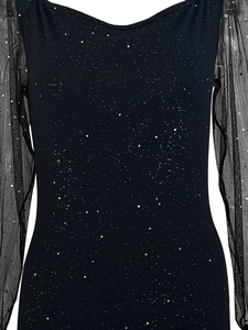 Detail showing elegant black sequin fabric and semi-transparent mesh sleeves on the dress