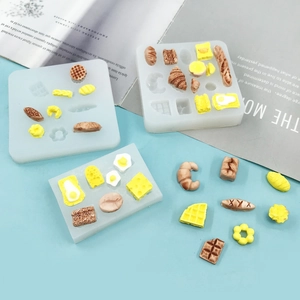 Mini silicone molds for croissants and waffles with miniature food models on blue background