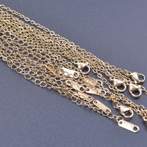 Dettaglio di catene a croce dorate in acciaio inossidabile con chiusure a moschettone