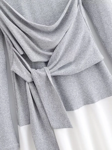 Detail of grey knit fabric with waist tie and white spliced hem on a stylish dress