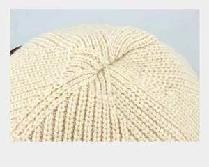Vue macro du bonnet en maille crème montrant les côtes et les détails de couture