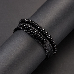 Detail of multi-layer black leather bracelet with braided rope and beads on a stand
