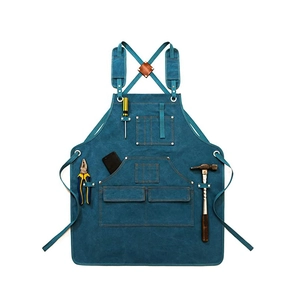 Detail view of blue canvas work apron with leather straps and multiple tool pockets