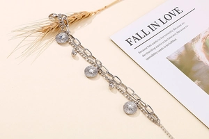 Detail of silver double-layer sunbeam coin charm bracelet with oval link chain