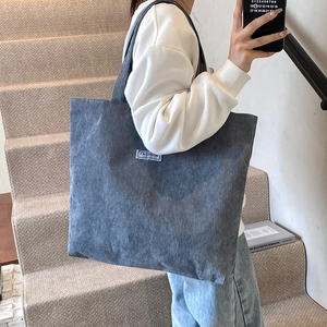 Gray corduroy tote bag shown on shoulder for capacity and textured detail reference