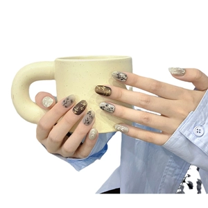 Handmade press-on nails with bamboo leaf design and gold foil in brown and cream white