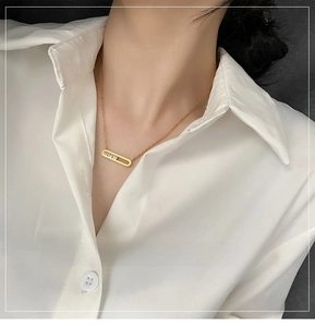 Close-up of a gold rectangle sliding zircon pendant necklace worn by a fashion model