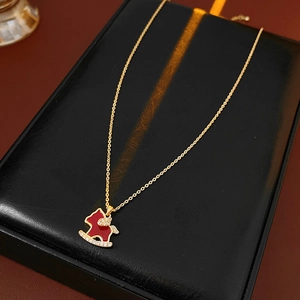 Close-up of gold-plated necklace with a red rocking horse pendant on a black box