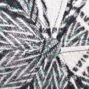 Macro shot of green and white wool plaid fabric texture with a top button on a baseball cap