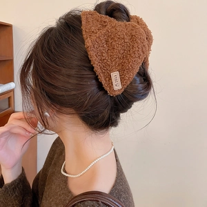 Detailopname van bruine pluche haarklem met berenlabel in het haar van het model